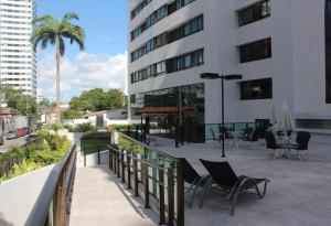 un balcón con sillas y mesas frente a un edificio en Flat 1402 com vista para mar, Edf Home Club Porto do Mar, en Recife