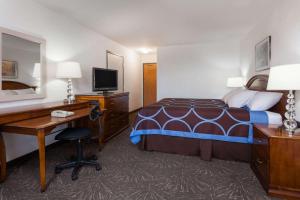 a hotel room with a bed and a desk and a computer at Super 8 by Wyndham Taber AB in Taber