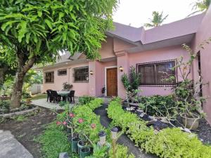 une maison rose avec un jardin devant elle dans l'établissement Magayon Pink House, à Legazpi