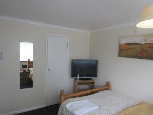 a bedroom with a bed and a flat screen tv at Serene Inn Near Bletchley Park in Bletchley