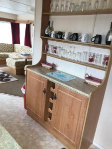 a kitchen with a counter and shelves with dishes at Caravan to Hire Dymchurch in Dymchurch