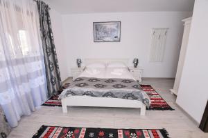 a bedroom with a white bed and a rug at Casa Alexandru – Locul în care te simți acasă in Vişeu de Jos