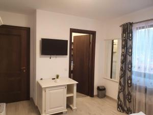 a room with a tv and a table and a door at Casa Alexandru – Locul în care te simți acasă in Vişeu de Jos