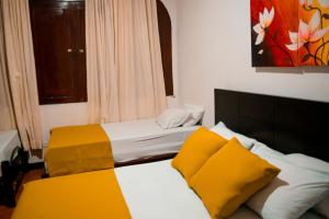 um quarto de hotel com duas camas com almofadas amarelas em Casabella Hotel em Manizales