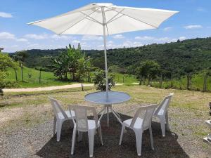 een tafel en stoelen met een witte parasol bij Casa de Campo-Linda Vista-SOUSAS in Campinas