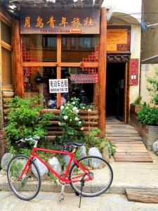 uma bicicleta vermelha estacionada em frente a um edifício em The Moon Bird Hostel em Shangri-La