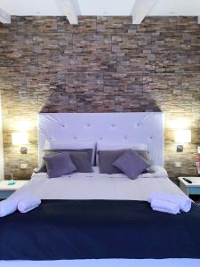 1 cama blanca grande en un dormitorio con pared de ladrillo en Locanda Domus De Vida Turismo Rurale, en Palau