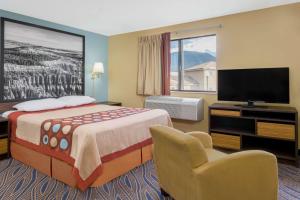 a hotel room with a bed and a flat screen tv at Super 8 by Wyndham Cedar City in Cedar City