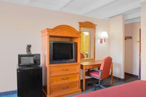 ein Hotelzimmer mit einem TV und einem Schreibtisch mit einem Computer in der Unterkunft Days Inn by Wyndham Tallahassee University Center in Tallahassee