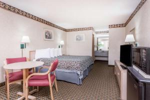 une chambre d'hôtel avec un lit, une table et des chaises dans l'établissement Days Inn by Wyndham Byron, à Byron