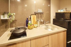 a kitchen counter with a sink and a microwave at MONday Apart Hamamatsucho Daimon in Tokyo