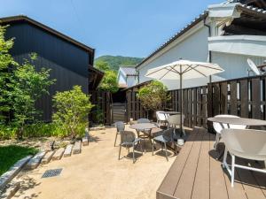 a patio with tables and chairs and an umbrella at 4S STAY Awaikeda Honmachi Street in Miyoshi