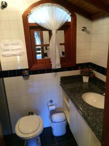 a bathroom with a toilet and a sink and a mirror at O Silêncio que Canta in Águas de Lindóia