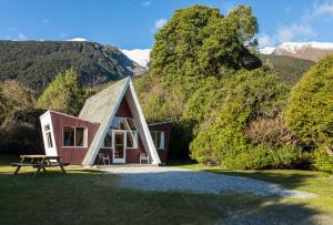 a cabin in the mountains with a picnic table in the grass at Wonderland Makarora Lodge in Makarora