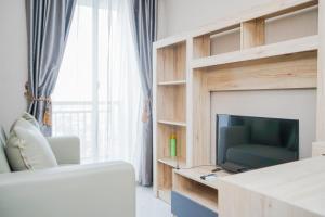 a living room with a television and a couch at New Furnished with City View 1BR at Akasa Pure Living BSD Apartment By Travelio in Ciater-hilir