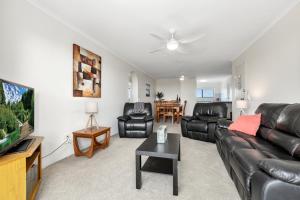 a living room with black leather furniture and a flat screen tv at Surfside Apartment 11 by Kingscliff Accommodation in Kingscliff