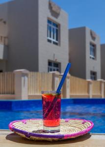 una bebida en un plato junto a una piscina en Al Asala Resort, en Al Ruwis