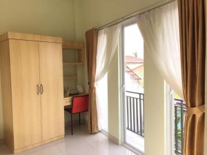 a room with a desk and a large sliding glass door at Hotel The Village Syariah in Pekanbaru