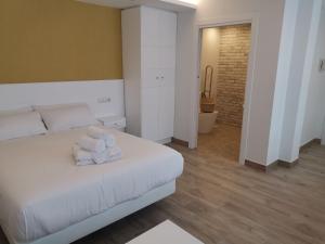 um quarto com uma cama branca e toalhas em Alumar Apartamentos Muxia em Muxía