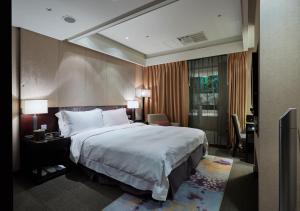 a hotel room with a large bed and a desk at The Tango Hotel Taipei XinYi in Taipei
