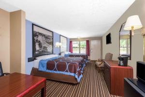 a hotel room with a bed and a tv at Super 8 by Wyndham Gadsden AL in Gadsden