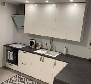 a kitchen with white cabinets and a sink at Apartament Spa - sauna i garaż w cenie in Ełk