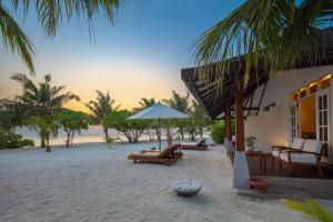 a house on the beach with a table and an umbrella at Adaaran Select Meedhupparu - with 24hrs Premium All Inclusive in Meedhoo