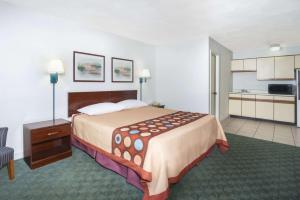 a hotel room with a large bed and a kitchen at Super 8 by Wyndham Taylorville IL in Taylorville