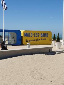 a sign on the beach with a train in the background at appartement malo les bains plage in Dunkerque