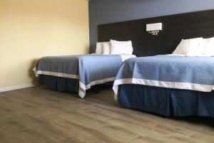 two beds in a room with a white bedspread at Days Inn by Wyndham Airport - Phoenix in Phoenix