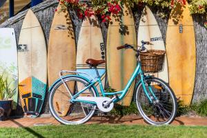 Una bicicleta azul estacionada junto a un montón de tablas de surf en The Carmel Yamba en Yamba