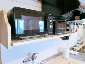 a microwave sitting on a shelf above a kitchen sink at Shirahama Meiji Villa in Shirahama