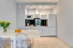 a white kitchen with a table and chairs at Hampton - Nadmorski Dwór in Gdańsk