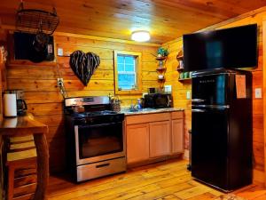 a kitchen with a black refrigerator and a stove at Lil' Log at Hearthstone Cabins and Camping - Pet Friendly in Helen
