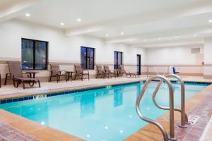 einen Pool mit Stühlen und Tischen in einem Gebäude in der Unterkunft Holiday Inn Express and Suites Missoula, an IHG Hotel in Missoula
