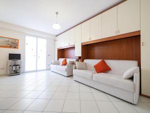 een woonkamer met twee witte banken en een tv bij Terrazza del Gelsomino with terrace and open view in Borghetto Santo Spirito