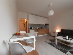 une cuisine et un salon avec une table et des chaises blanches dans l'établissement Apartamenty Lewa, à Łódź