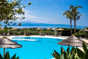 a pool with umbrellas and the ocean in the background at Hotel Santa Chiara in Capo Vaticano