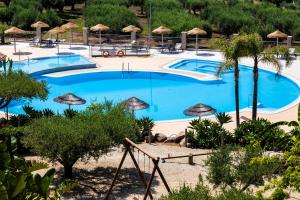 a large blue pool with umbrellas and trees at Hotel Santa Chiara in Capo Vaticano