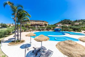 a pool with umbrellas and chairs and a resort at Hotel Santa Chiara in Capo Vaticano