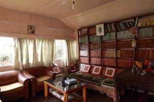 a living room with a couch and book shelves at Pradhan's Cottages in Darjeeling