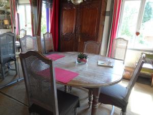 a dining room table with chairs and a wooden table with a plant on it at La Roseraie du Prieure in Rosay-sur-Lieure