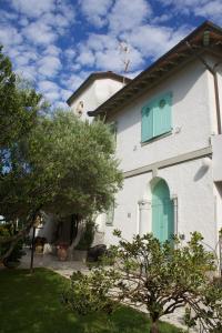 a white house with a green door and trees at Hotel Poseidon in Marina di Pietrasanta