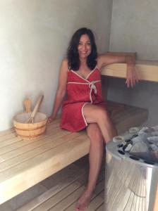 uma mulher de vestido vermelho sentada num banco de sauna em Locanda di Terramare em Gabbro
