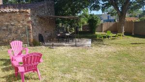 2 rosa Stühle und ein Tisch im Hof in der Unterkunft Les Belles Nuits in Le Bousquet-dʼOrb