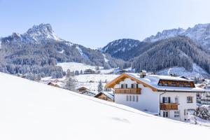 a house in the snow with mountains in the background at Garni Charlotte in Selva di Val Gardena