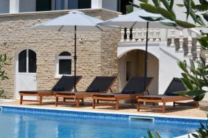 a pool with two lounge chairs and an umbrella at Holiday Home Nevera in Kaštela