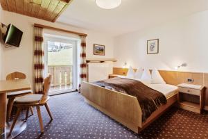 a hotel room with a bed and a desk and a window at Garni Charlotte in Selva di Val Gardena