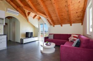 a living room with a purple couch and a tv at Holiday Home Nevera in Kaštela