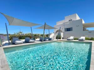 a swimming pool with chairs and umbrellas in front of a house at Seaside Naxos • Holiday Villas in Plaka